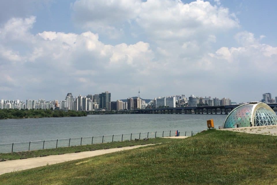 한강시민공원 여의도지구(여의도 한강공원)1 : 한강 너머로 고층 빌딩이 보이는 공원 전경