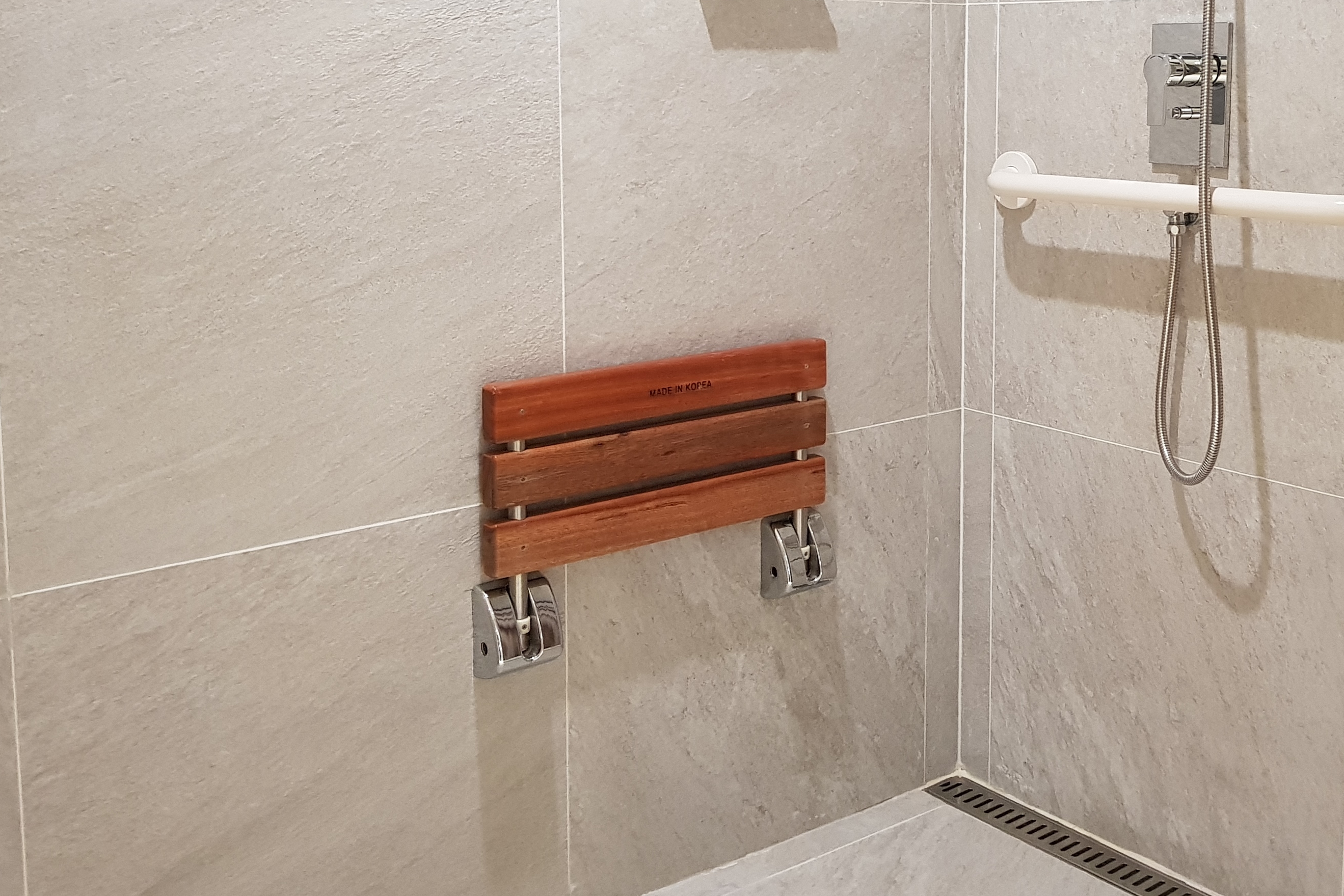 샤워의자0 : 샤워의자가 설치되어 있는 노보텔 앰배서더 용산 호텔 화장실 전경