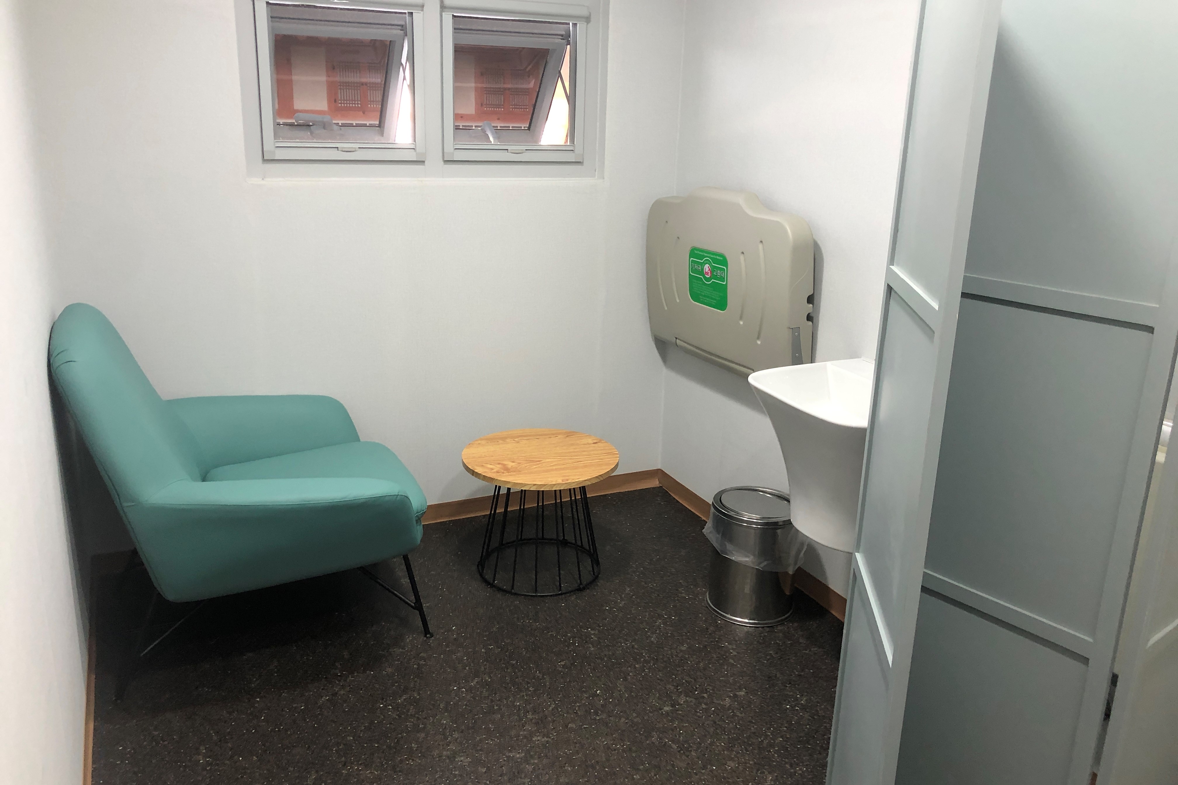 Expecting mothers and children resting area 0 : Nursing room with a single sofa and a diaper changing station seen through foldable door
