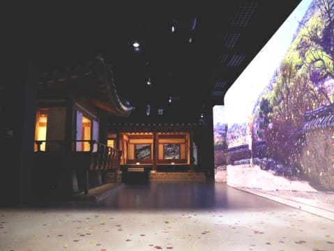 박물관 내 설치된 전통 가옥과 우측 미디어 화면의 돌담 풍경