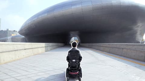 동대문 디자인 플라자를 거닐고 있는 휠체어를 탄 남성의 뒷모습
