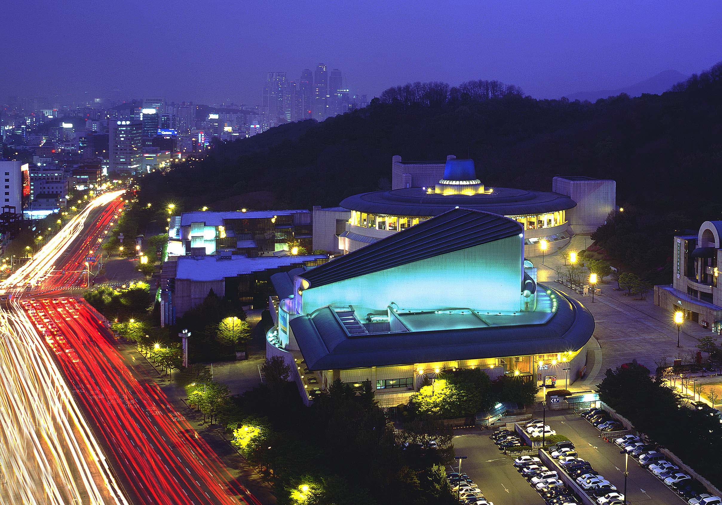 Music Hall, Seoul Arts Center2 : Exterior night view of the Music Hall at Seoul Arts Center with blue lights on the front of the building and car lights on the road