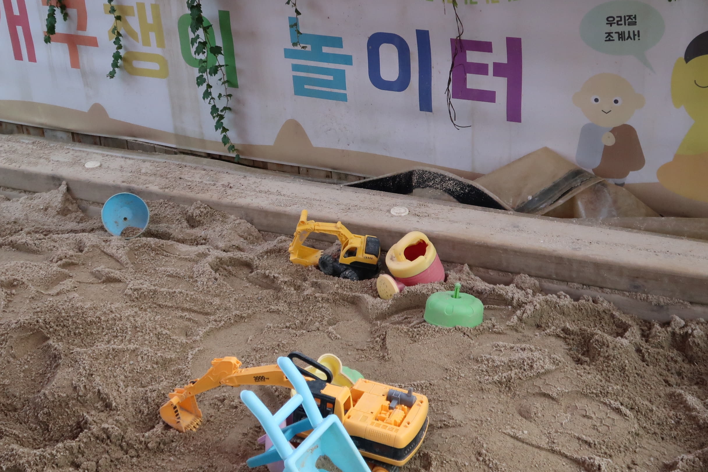 어린이 놀이시설0 : 모래가 깔린 놀이터 곳곳에 놓인 장난감들