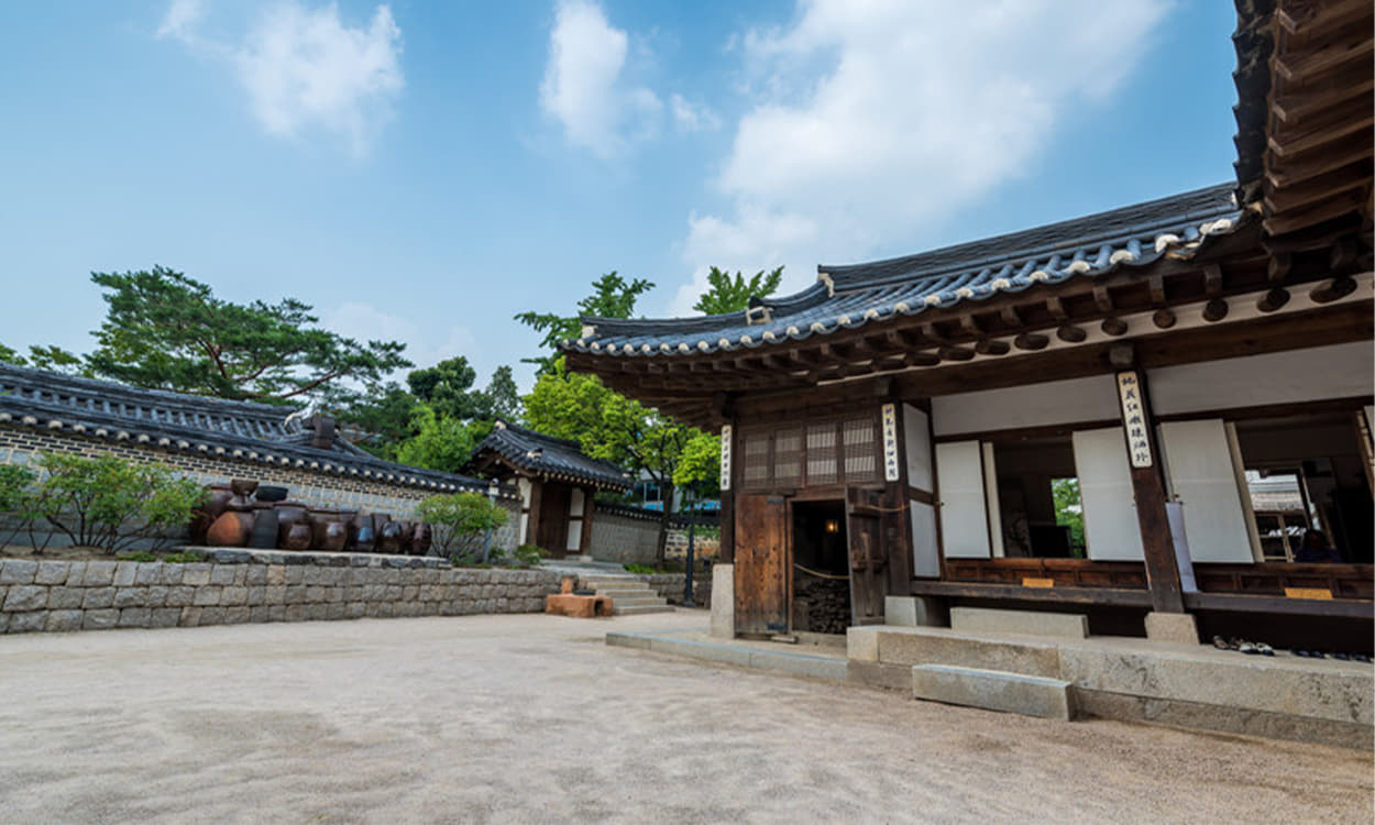 Namsangol Hanok Village1 : A traditional tile-roofed house surrounded by a wall in the background of clear sky 