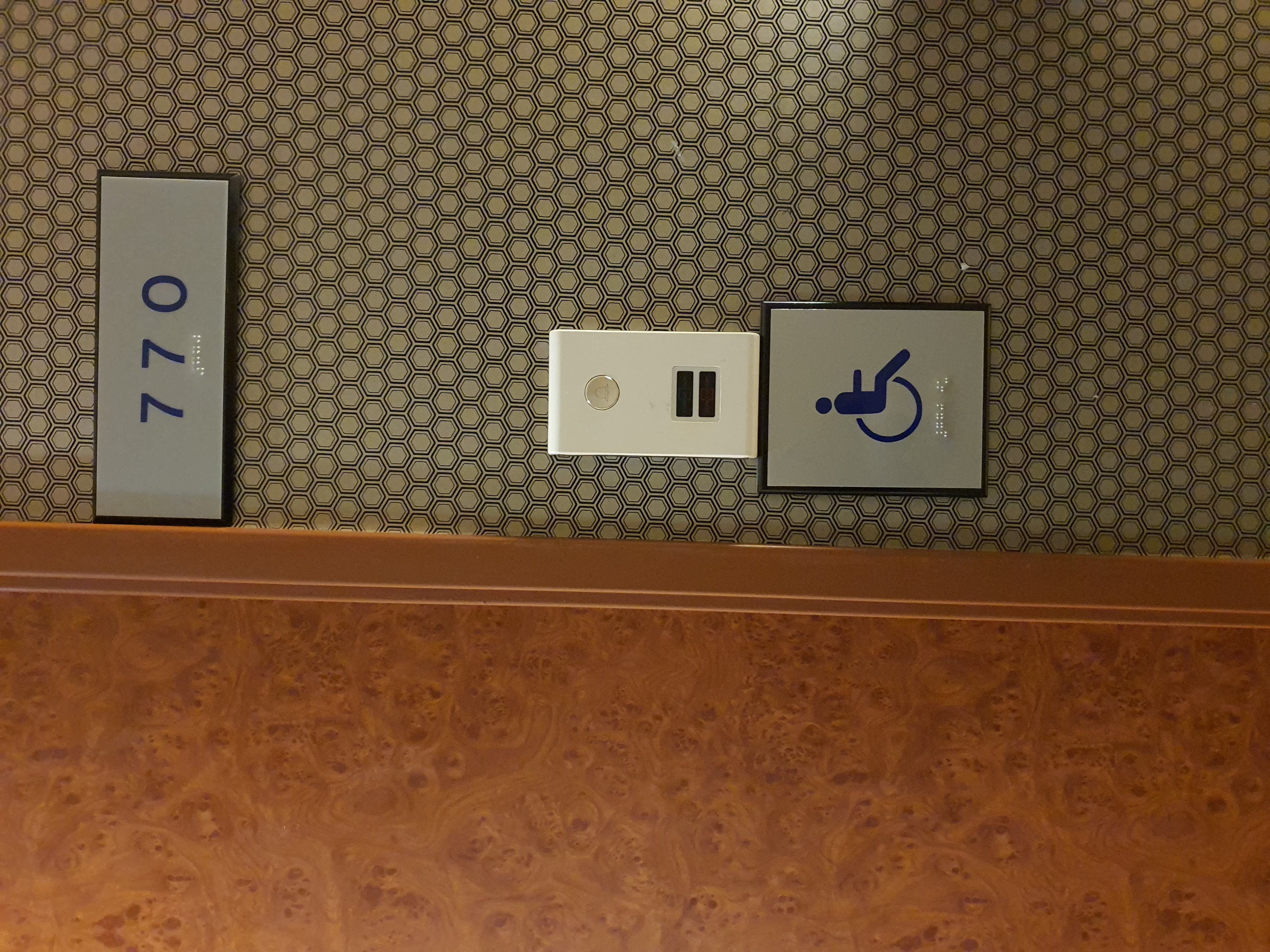 Accessible guestroom0 : The hotel room door with braille signages of the room number and the wheelchair pictogram