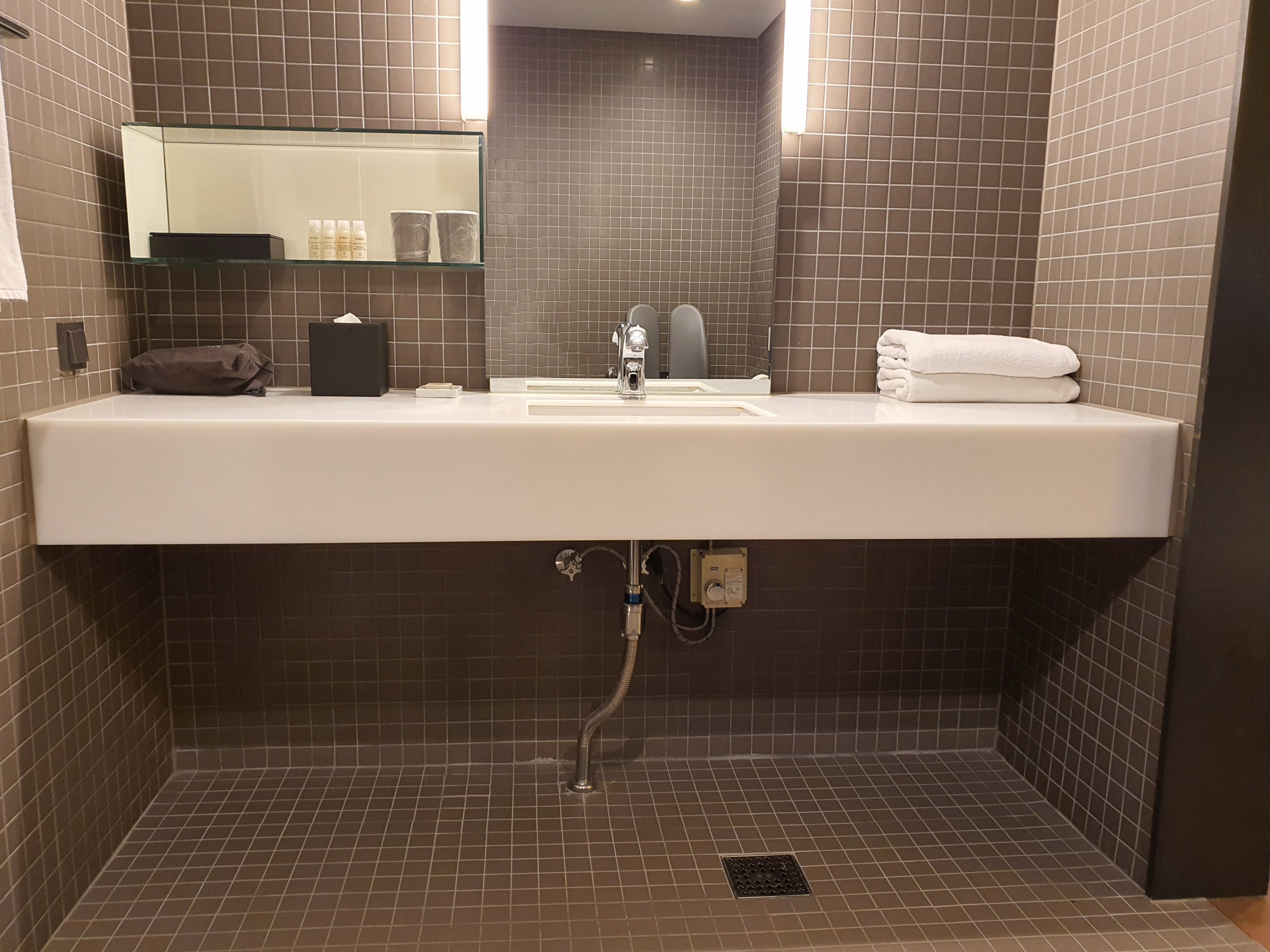 Accessible restroom in the guestroom0 : a wide wall-mounted bathroom sink with no cabinet underneath