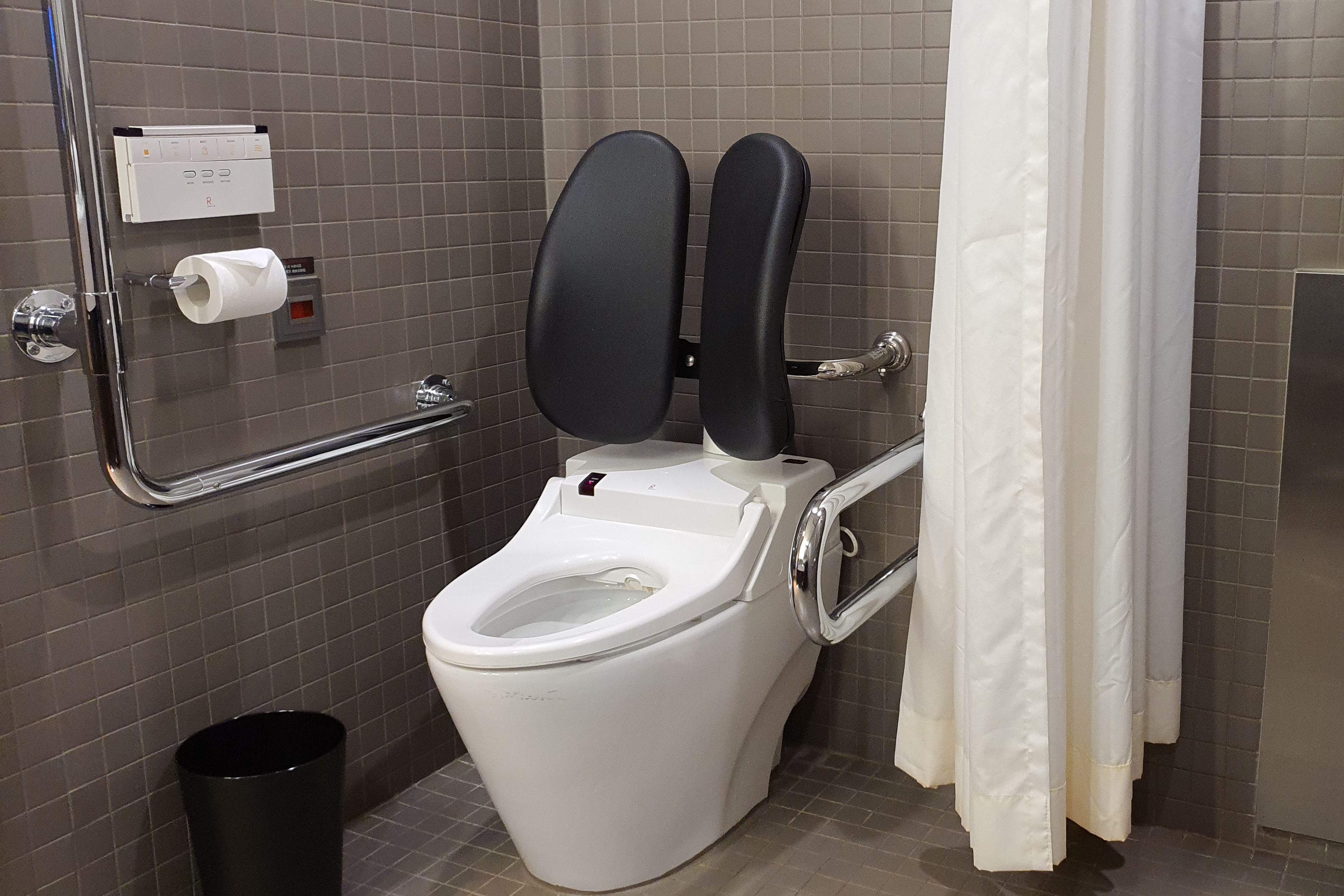Bathroom in the guestroom 0 : A toilet equipped with grab bars in the separated area by a curtain