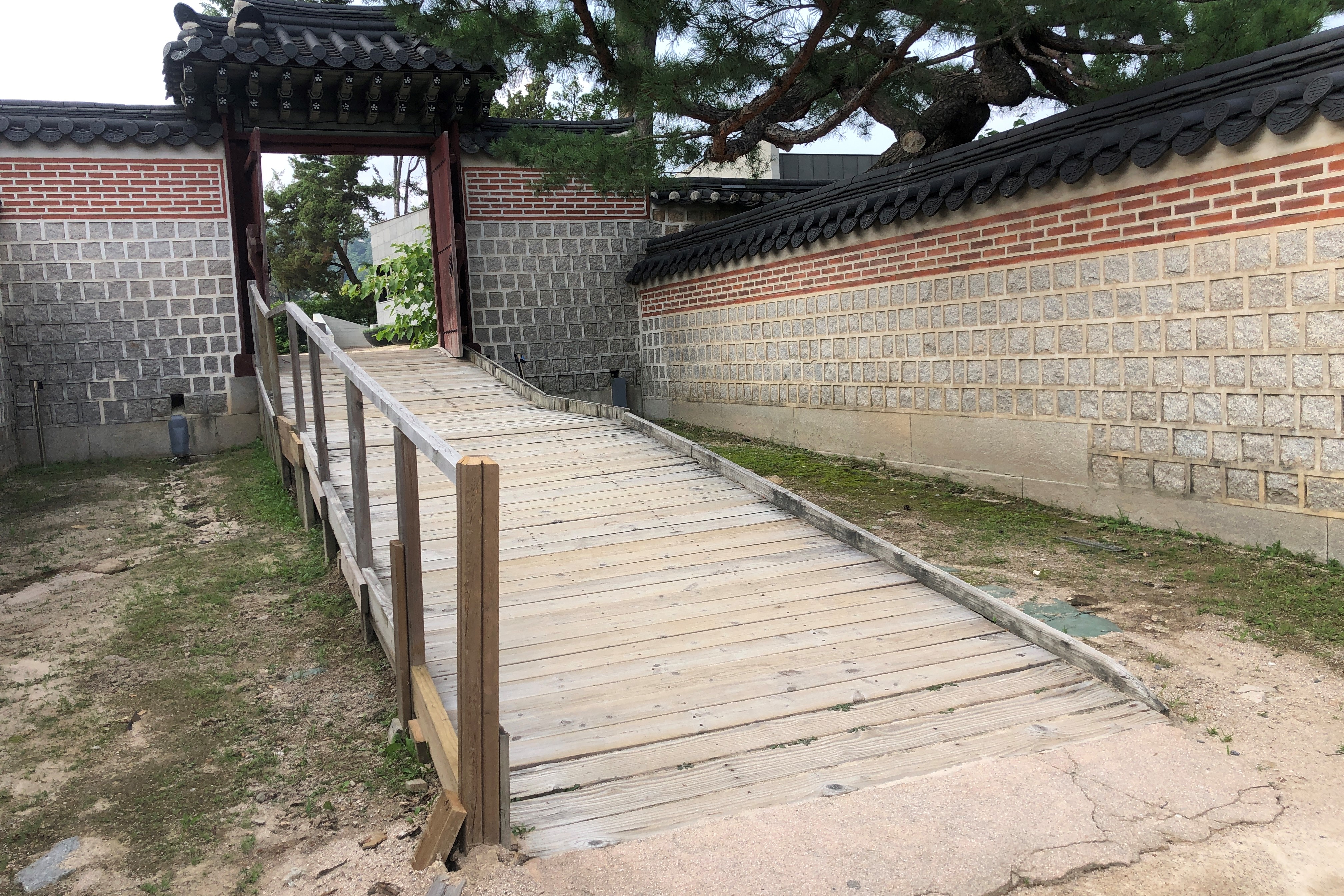Entryway/ Main entrance0 : A long wooden ramp installed in a passageway between walls
