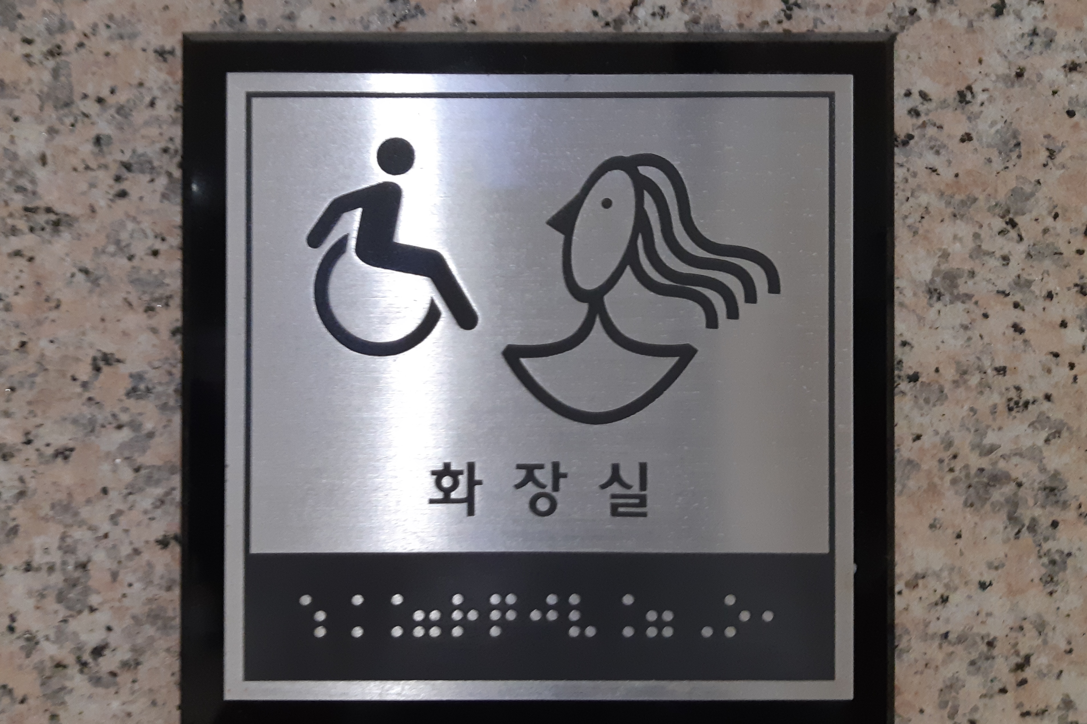 Accessible restroom for persons with disabilities0 : Sign on the wall about accessible restroom with wheelchair, woman symbol and Korean breille