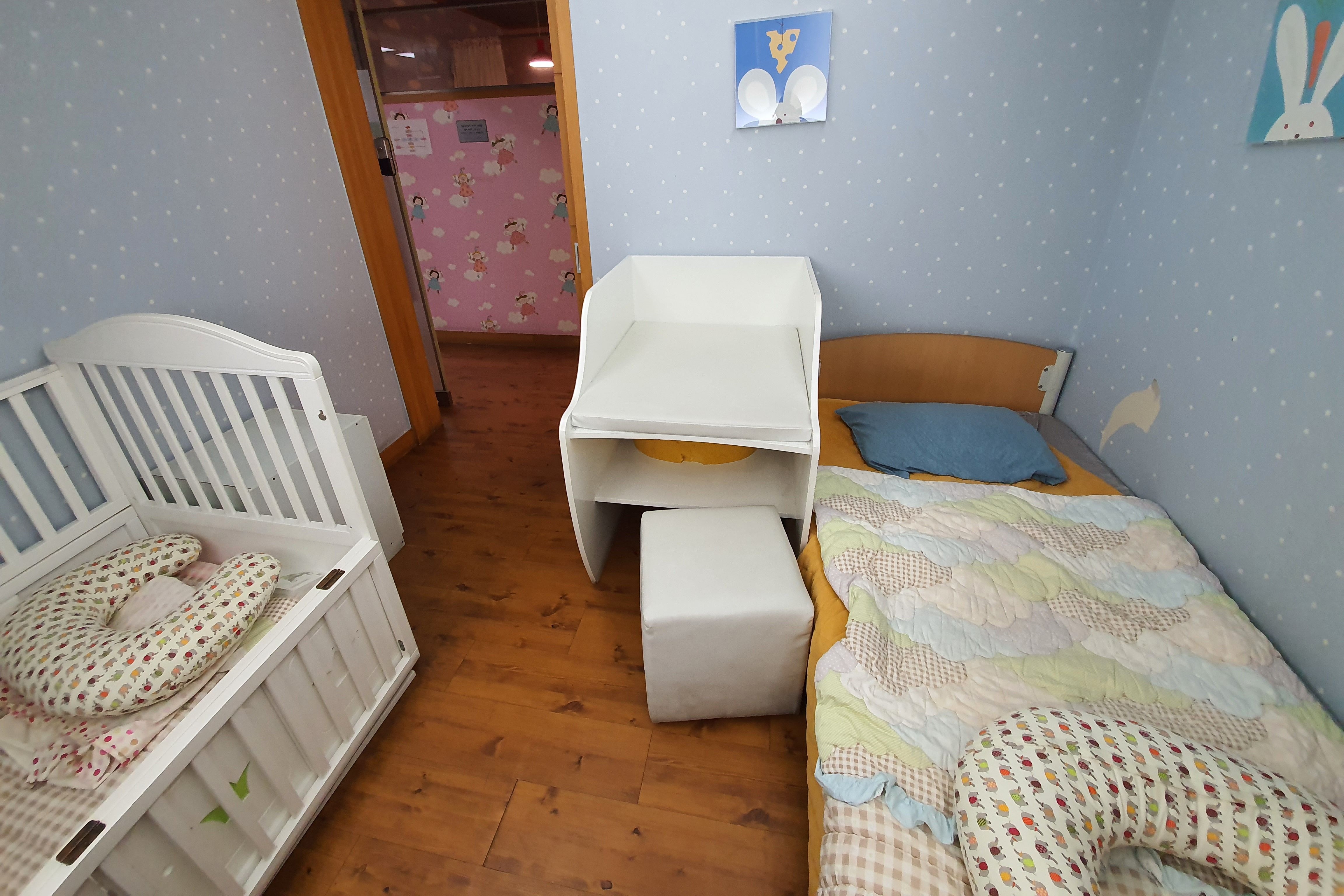 Nursing room0 : interior view of the nursing room with diaper changing station, baby bed, adult-sized beds and bedding