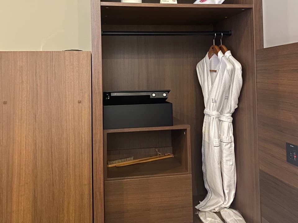 Accessible guestroom0 : Oak colored built-in cabinet with a safe and robes