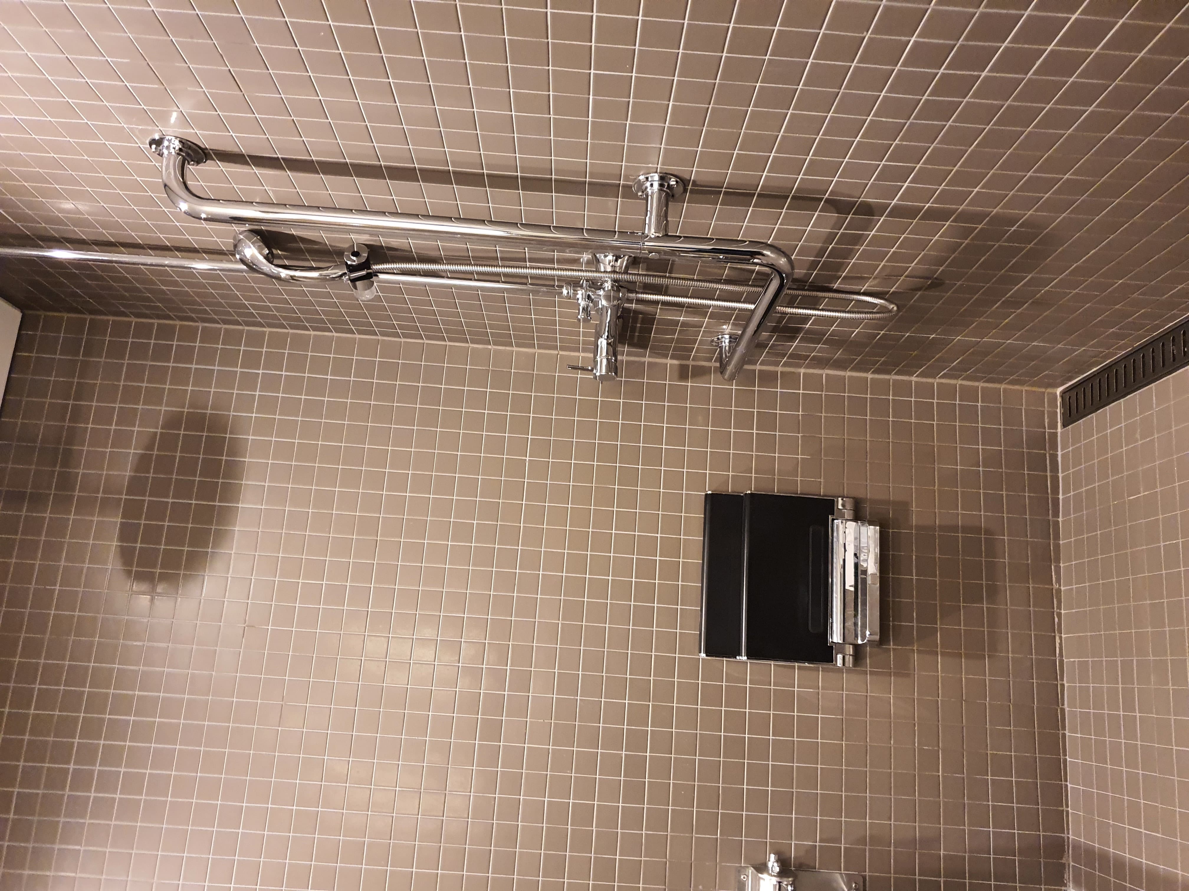 Accessible restroom in the guestroom0 : A roll-in shower with a wall-mounted chair and a shower faucet