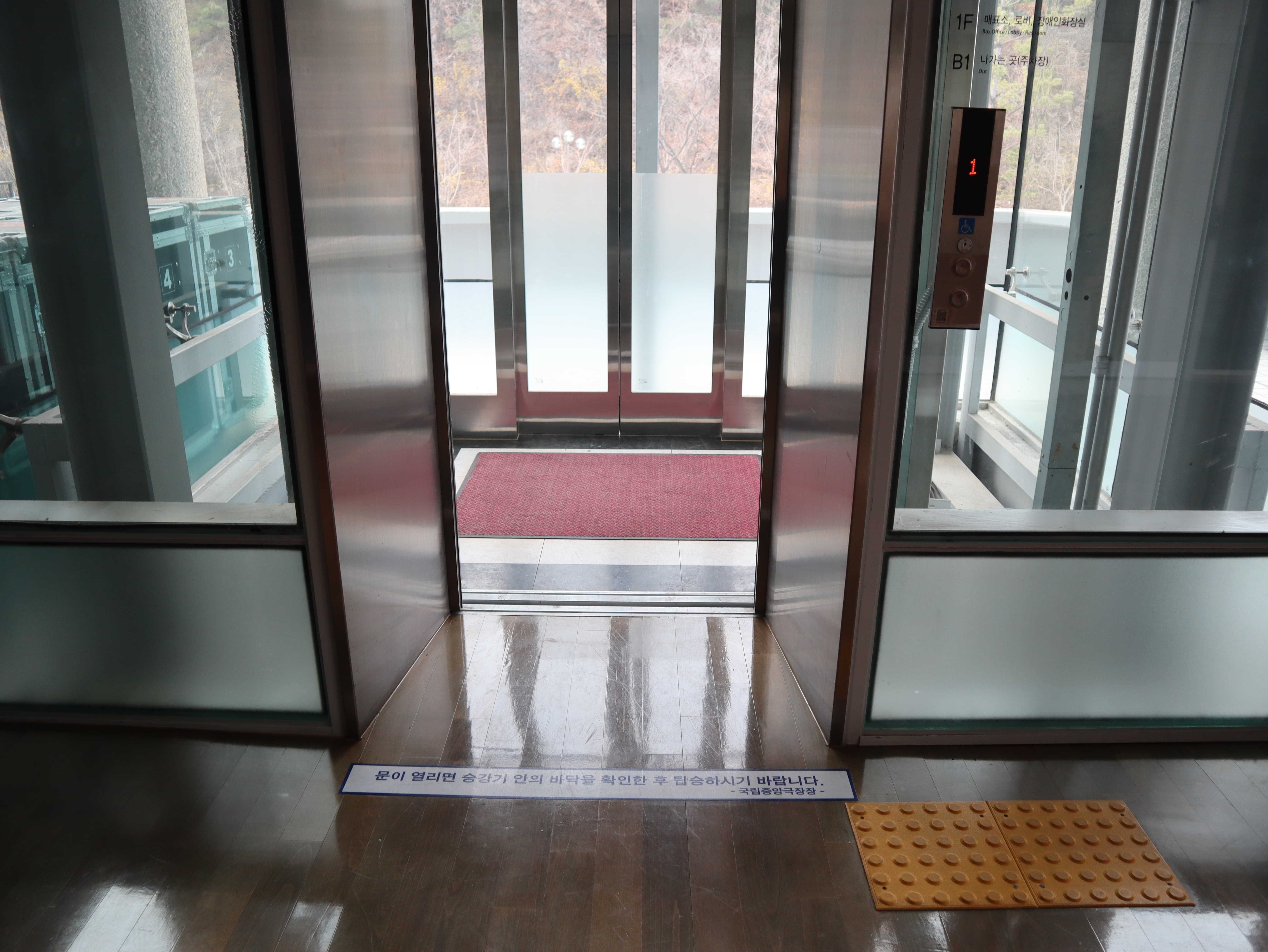 달오름극장 편의시설0 : 전면이 유리인 엘리베이터와 문 우측의 점자 블록